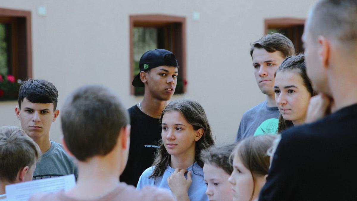 Teenagers gathered outdoors engaged in a lively discussion, fostering communication and learning.